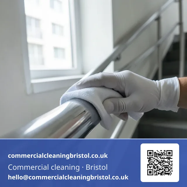 Gloved hand wiping a stairwell handrail in one continuous pass with a folded microfibre cloth